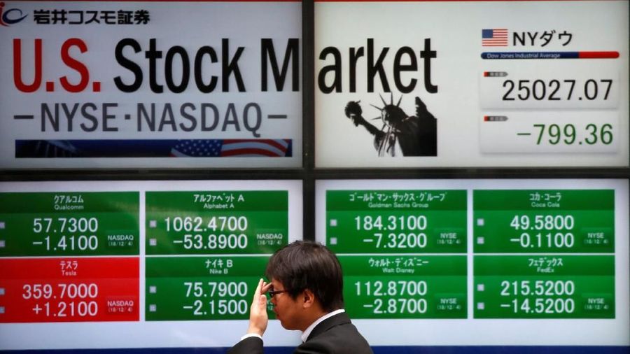A man walks past an electronic board showing U.S. stock market indicators outside a brokerage in Tokyo, Japan, December 5, 2018.  REUTERS/Issei Kato