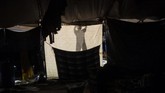 Setelah hujan deras usai, bayangan seorang imigran yang berjalan selama sebulan penuh melintasi Amerika Tengah dan Meksiko dengan menggunakan karavan, terlihat di sebuah penampungan sementara di Tijuana, Baja California, dekat dengan perbatasan Amerika Serikat. (Photo by Pedro PARDO / AFP)