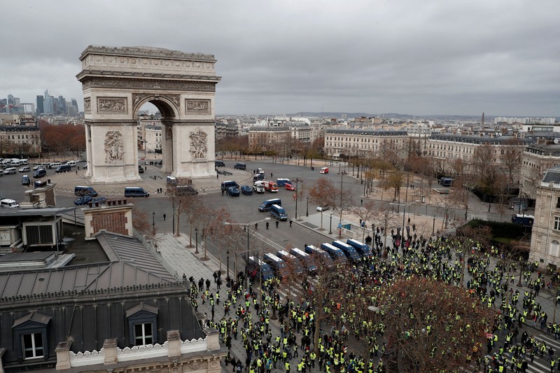 Protesters wearing yellow vest, a symbol of a French drivers' protest against higher fuel prices, stand up in front of a police water canon during clashes on the Champs-Elysees in Paris, France, November 24, 2018. REUTERS/Benoit Tessier