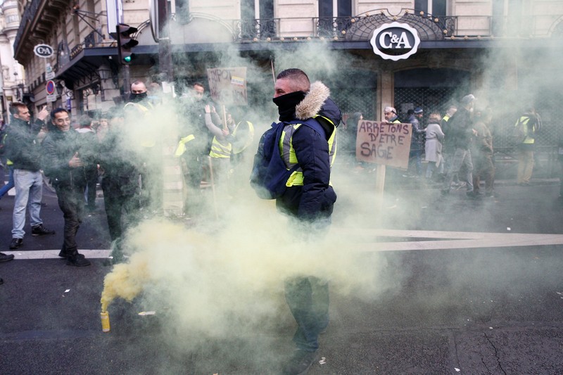 Protesters wearing yellow vest, a symbol of a French drivers' protest against higher fuel prices, stand up in front of a police water canon during clashes on the Champs-Elysees in Paris, France, November 24, 2018. REUTERS/Benoit Tessier