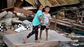 Zidan (kanan) dan Caca berpose di depan rumahnya yang rusak akibat gempa dan tsunami di Wani, Donggala, Sulawesi Tengah. BNPB mencatat penghitungan kerugian per 27 Oktober 2018 akibat gempa palu mencapai sekitar Rp18,4 triliun. (ANTARA FOTO/Wahyu Putro A)