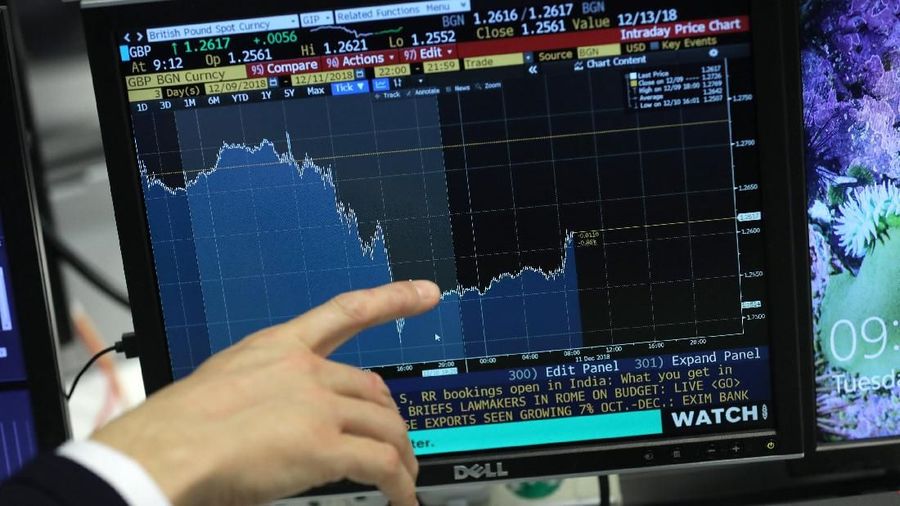 A trader works as screens show market data at CMC markets in London, Britain, December 11, 2018. REUTERS/Simon Dawson