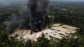 Tak mampu menyita langsung mesin tambang yang ada di lapangan, para agen akhirnya memutuskan untuk membakarnya, membuat asap mengepul di sekitar hutan. (Reuters/Ricardo Moraes)