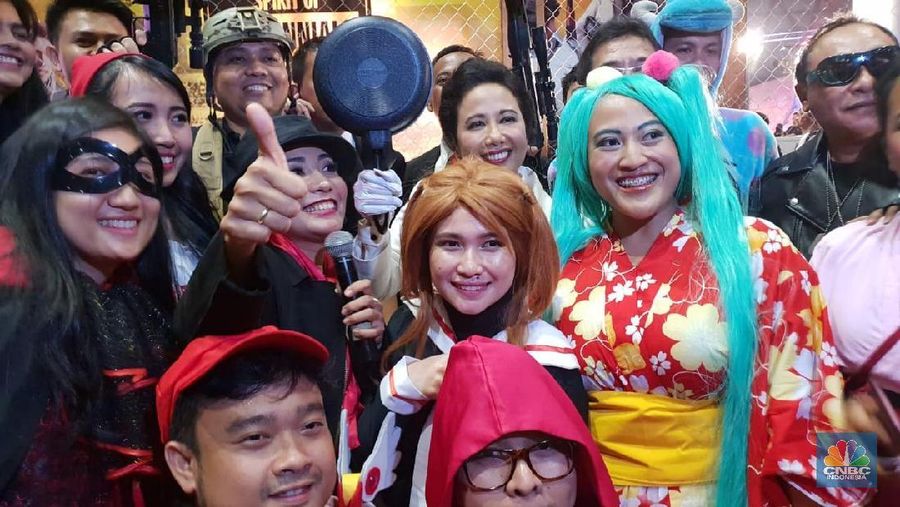 Gaya Menteri Rini datang dengan Jas Putih dasi oren dan membawa peralatan masakan.