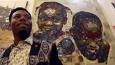 Koffi berpose di depan karya seni yang dibuatnya dari tumpukan sampah elektronik, yang kerap dipandang sebelah mata setelah dianggap tak berguna. (REUTERS/Luc Gnago)