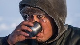 Beberapa warga terbiasa meminumnya mentah. Namun, beberapa warga yang lain memilih untuk memanaskannya terlebih dahulu. Menurut mereka, air dari balok es yang meleleh begitu saja tak punya banyak kandungan kalsium dan magnesium yang diperlukan tubuh. (Photo by Mladen ANTONOV/AFP)