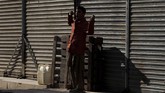Seorang bocah laki-laki menguap di bawah sinar matahari di depan toko-toko yang tutup pada pagi hari di Karachi, Pakistan. Pertumbuhan ekonomi Pakistan diperkirakan mencapai titik terendah sembilan tahun, merosot ke hampir 2,9 persen. (REUTERS/Akhtar Soomro)