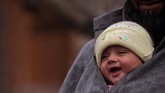 Di suatu hari di musim dingin, seorang pria di distrik selatan Kashmir membawa bayi di pelukan. (REUTERS/Danish Ismail)
