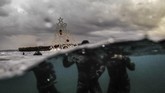 Para penyelam bebas berpose dengan pohon natal berornamen sebelum kembali menyelam dan menempatkan pohon natal itu di dasar laut perairan utara kota Tripoli, Libanon. (Photo by IBRAHIM CHALHOUB / AFP)