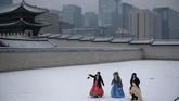 Turis berpakaian tradisional Korea Selatan, hanbok, melintas di komplek Istana Gyeongbokgung yang diselimuti salju.