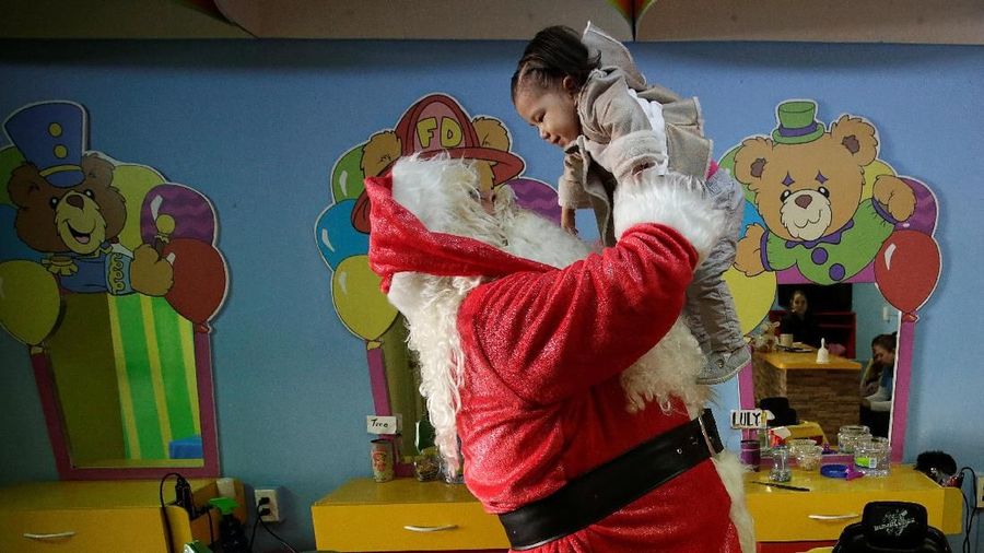 The owner of a kids hair salon, dressed as Santa Claus, holds up a child in Monterrey, Mexico December 19, 2018. REUTERS/Daniel Becerril