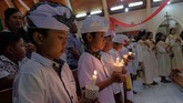 Sejumlah anak berbusana adat Bali membawa lilin saat mengikuti prosesi misa malam Natal di Gereja Katolik Hati Kudus Yesus Palasari, Jembrana, Bali, Senin (24/12/2018). Misa malam Natal dengan berpakaian adat Bali merupakan tradisi umat Katolik di Desa Palasari sebagai simbol akulturasi. (ANTARA FOTO/Nyoman Hendra Wibowo/nym/kye)