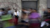 Satu pria hanya bisa bersandar di tembok ketika orang lain berlarian di tengah situasi padam listrik di Caracas. (Photo by FEDERICO PARRA / AFP)