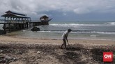 Emi Suryo, pemilik resort membersihkan sisa dahan dan ranting pohon yang terbawa gelombang tsunami di kawasan Anyer, Serang, Banten, 27 Desember 2018. Emi tetap optimis usaha resortnya bisa bangkit. (CNNIndonesia/Safir Makki)