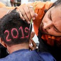 Seorang pria mengaplikasikan warna pada potongan rambut dengan nomor "2019", digambarkan untuk menyambut tahun baru di sebuah tempat pangkas rambut di Ahmedabad, India, 30 Desember 2018. REUTERS / Amit Dave