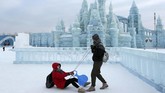 Turis berfoto di depan bangunan yang berasal dari pahatan es di festival musim dingin di Harbin, China.