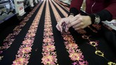 Warga Palestina bekerja pada selembar kain panjang yang digunakan untuk membuat gaun tradisional di sebuah pabrik di Ramallah. (REUTERS/Raneen Sawafta)