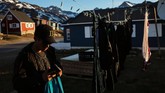 Seorang warga mencuci baju saat matahari bersinar hangat di kota Tasiilaq, Greenland.