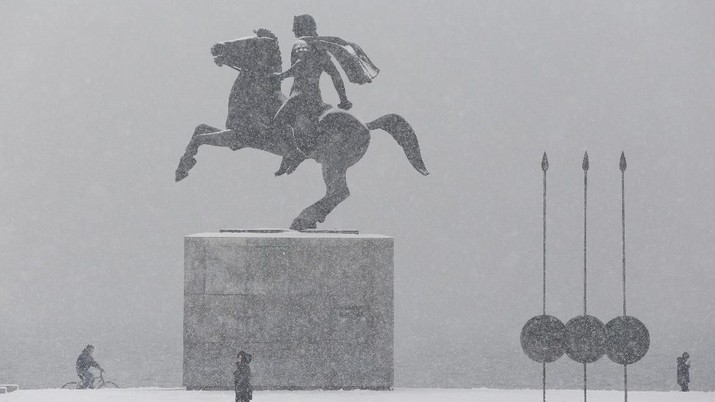 People make their way at the seaside promenade as snow covers the statue of Alexander the Great in Thessaloniki, Greece, January 9, 2019. REUTERS/Alexandros Avramidis