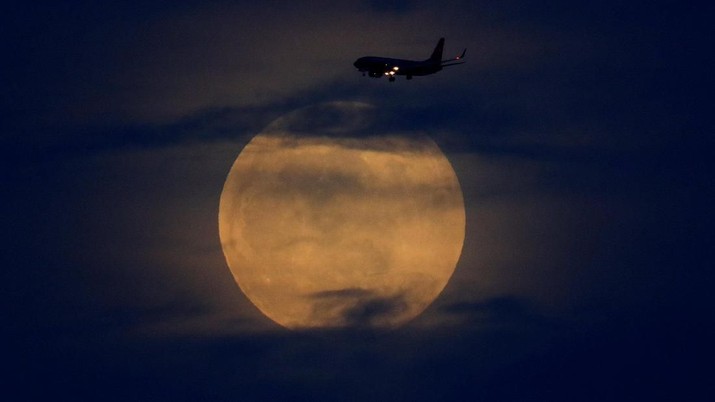 Gerhana Bulan di San Diego, California, US (Reuters/Mike Blake) A full moon rises between clouds as a landing commercial jet approaches the airport before the start of a total lunar eclipse that is being called a 'Super Blood Wolf Moon' in San Diego, California, U.S., January 20, 2019. REUTERS/Mike Blake