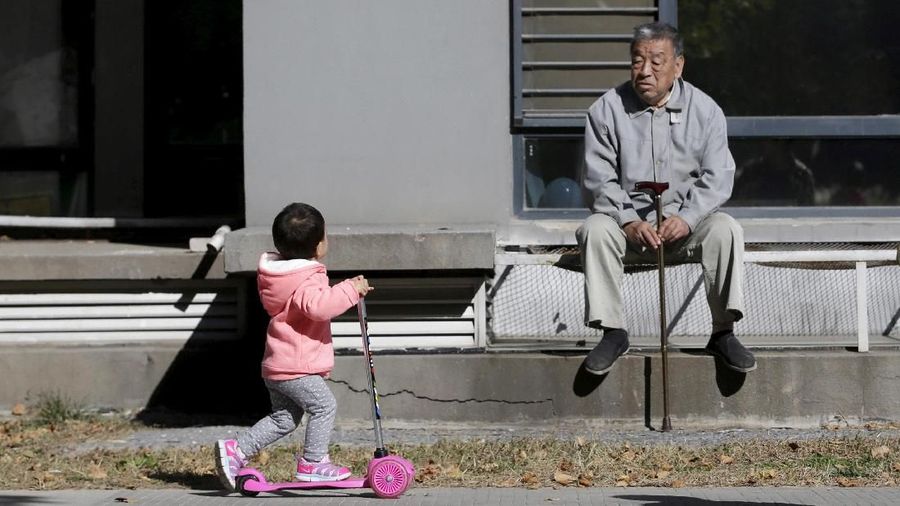 FILE PHOTO: An 80-year-old man, surnamed Li, watches as a girl plays at a residential community in Beijing, China, October 30, 2015. REUTERS/Jason Lee/File Photo