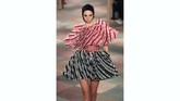 Gaun-gaun lipit berwarna pink, emas, dan hijau terlihat melayang di atas runway, begitu pula dengan beberapa gaun berbahan tulle dengan sulaman rumit serta bodysuit bermotif tato. (REUTERS/Gonzalo Fuentes)