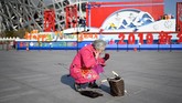 Demikian pula halnya dengan yang dilakukan seorang pensiunan bernama Wang Jinxiang, 62 tahun ini. Bedanya, ia menyiarkan penampilannya itu secara live melalui ponsel. (Photo by WANG ZHAO/AFP)
