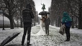 Bahkan pasangan pengantin memanfaatkan guyuran salju sebagai latar belakang berfoto. (Photo by Lionel BONAVENTURE / AFP)