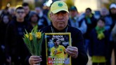 Seorang pria memegang majalah olahraga dan bunga tulip dalam doa bersama di kota Nantes. (REUTERS/Stephane Mahe)