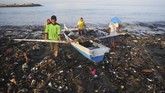 Nelayan menepikan perahunya melewati tumpukan sampah yang berserakan di Pantai Muara Lasak, Padang, Sumatera Barat, Kamis (24/1/2019). Nelayan mengeluhkan sampah dari hulu yang bertumpuk sejak Senin (22/1) karena menghambat akses perahu mereka untuk pergi melaut. ANTARA FOTO/Iggoy el Fitra/aww/