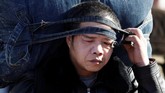 Seorang pemudik membawa tas besar menuju East Railway Station di Zhejiang, China. (REUTERS/Jason Lee)