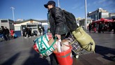Di Stasiun Kereta Api Beijing pada Rabu (30/1) pagi, ribuan orang berseliweran dalam cuaca dingin, terbungkus mantel tebal sambil membawa barang bawaan mereka. (REUTERS/Jason Lee)