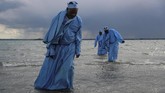 Jemaat senior Gereja Apostles Of Muchinjikwa meninggalkan laut setelah memimpin baptis massal di pantai di Inggris. (REUTERS/Simon Dawson)