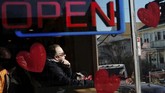 Sinar matahari menerpa wajah seorang pria yang sedang duduk di suatu kedai kopi berdekorasi hari Valentine di Massachusetts, Amerika Serikat. (REUTERS/Brian Snyder)
