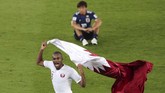 Pemandangan kontras terlihat ketika Hassan Abdelkarim mengibarkan bendera Qatar sementara Takashi Inui terduduk. (REUTERS/Ahmed Jadallah TPX IMAGES OF THE DAY)