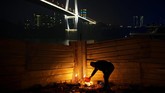 Seorang lelaki membakar kertas-kertas dupa untuk berdoa agar mendapat keberuntungan pada malam Tahun Baru Imlek Babi Cina, di sebuah kuil dekat jembatan di atas Sungai Yangtze, di Chongqing, China. (REUTERS/Stringer)