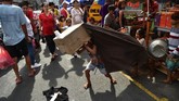 Anak-anak melakukan tarian singa dengan kepala singa yang dibuat dari karton, menghibur pejalan kaki di distrik Chinatown, Manila. (AFP/Ted Aljibe)