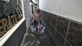 Bagi warga yang tinggal di kawasan langganan banjir, musim hujan berarti mereka harus siap-siap kebanjiran. Seorang warga Rawa Buaya, Jakarta Barat tampak melintasi genangan air yang tercipta saat hujan deras turun. (ANTARA FOTO/Rivan Awal Lingga)