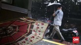 Warga melintas menggunakan payung untuk melindungi diri dari hujan di kawasan bisnis Sudirman, Jakarta. Hujan yang hampir turun setiap hari membuat warga harus menyiapkan payung saat berpergian. (CNN Indonesia/Harvey Darian)