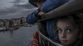 Di atas feri Kadikoy di Bosphorus, Turki, seorang gadis kecil di sela-sela tubuh abangnya melihat ke atas. (Photo by BULENT KILIC / AFP)