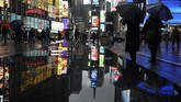 Bayangan orang-orang tercermin di tembok yang terkena hujan di Times Square di New York. Suhu pada awal pekan ini telah kembali ke digit tunggal dan tertinggi selama dua pekan terakhir yaitu 10 derajat celcius. (Photo by TIMOTHY A. CLARY / AFP)