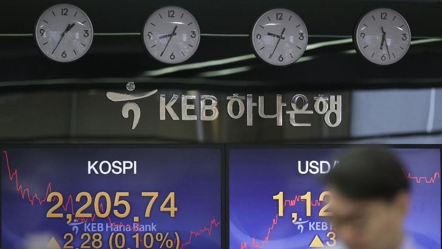 A currency trader walks by screens showing the Korea Composite Stock Price Index (KOSPI), left, and the foreign exchange rate between U.S. dollar and South Korean won at the foreign exchange dealing room in Seoul, South Korea, Thursday, Feb. 7, 2019. Asian shares were mostly higher Thursday on news that the Reserve Bank of Australia may cut interest rates, driving hopes that other central banks could come to the same conclusion. (AP Photo/Lee Jin-man)