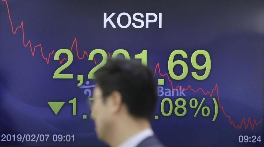 A currency trader walks by screens showing the Korea Composite Stock Price Index (KOSPI), left, and the foreign exchange rate between U.S. dollar and South Korean won at the foreign exchange dealing room in Seoul, South Korea, Thursday, Feb. 7, 2019. Asian shares were mostly higher Thursday on news that the Reserve Bank of Australia may cut interest rates, driving hopes that other central banks could come to the same conclusion. (AP Photo/Lee Jin-man)