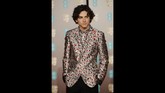 Timothee Chalamet berani tampil beda dengan jas uniknya. Dia memakai jas dan kemeja yang bermotif senada dari Haider Ackerman. (Photo by Tolga AKMEN / AFP)