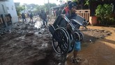 Seorang warga membawa kursi roda di komplek perumahan Jati Endah Regency, Pasir Jati, Cilengkrang, Kabupaten Bandung, Jawa Barat, pasca diterjang banjir bandang, Minggu (10/2/2019). ANTARA FOTO/Raisan Al Farisi/ama.