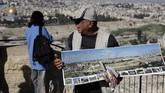 Penjaja oleh-oleh membuka peta Kota Lama Yerusalem yang menjadi barang jualannya. (AFP/THOMAS COEX)