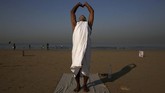 Krishna Das, pria India berusia 58 tahun yang selama 10 tahun terakhir berusaha menyebarkan pesan kedamaian dengan menaruh plakat di tepi pantai. Dia melakukan yoga setelah meletakkan plakat di Mumbai, India. (REUTERS/Francis Mascarenhas)