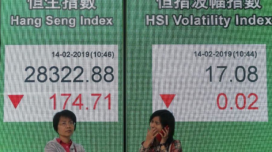 Two women stand in front of an electronic board showing Hong Kong share index outside a bank in Hong Kong, Thursday, Feb. 14, 2019. Asian stocks were mostly lower on Thursday as China and the U.S. kicked off two days of trade negotiations in Beijing. (AP Photo/Kin Cheung)