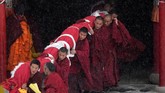 Para biksu bersama-sama menggotong thangka Budha raksasa ke lereng bukit sebrang biara. (REUTERS/Aly Song)