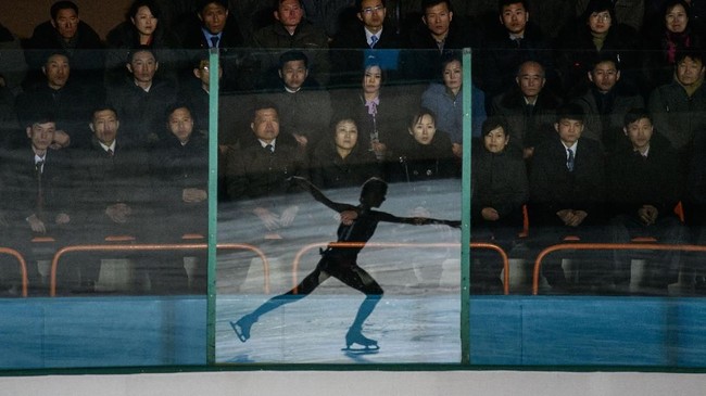 Bayangan seorang atlet seluncur es tercermin di suatu panel kaca, ketika para penonton menyaksikan Festival Seluncur Es Paektusan ke-26 di Pyongyang, Korea Utara. Festival ini merupakan rangkaian acara perayaan ulang tahun mendiang mantan pemimpin Korea Utara, Kim Jong Il. (Photo by Ed JONES / AFP)